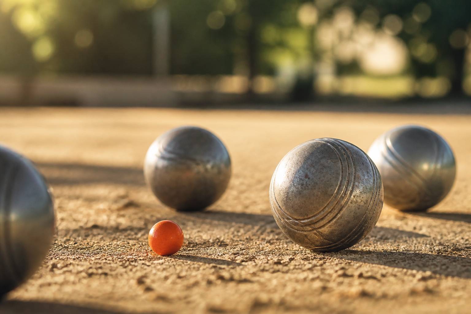 Boules de pétanque en acier près du cochonnet sur de la terre battue ocre