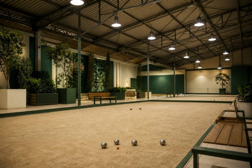 Intérieur de boulodrome couvert avec allées de terre battue sous charpente