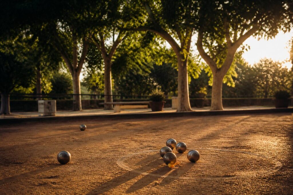 Boulodrome en fin d'après-midi avec un terrain de terre battue et des boules de pétanque au sol