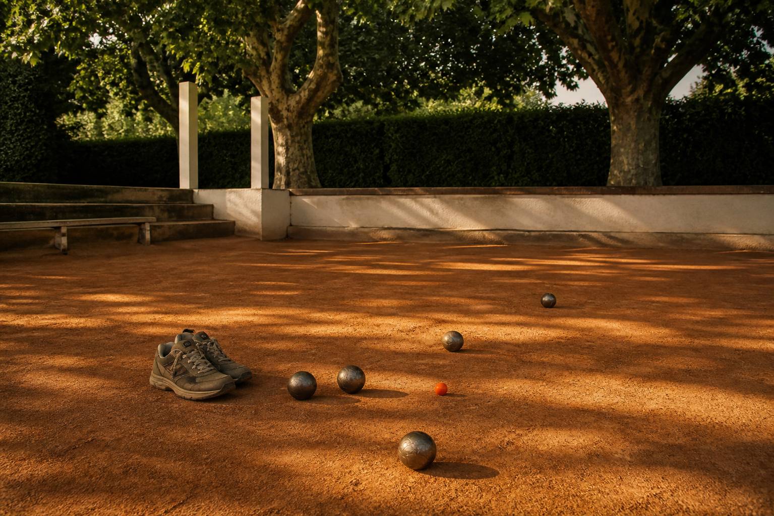 Chaussures fermées de sport et boules de pétanque sur un terrain ocre