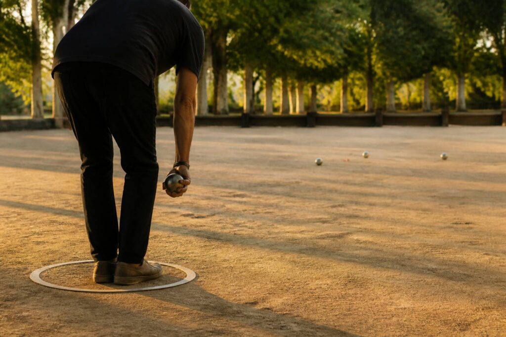 Joueur de pétanque vu de dos les pieds dans le cercle de lancer réglementaire