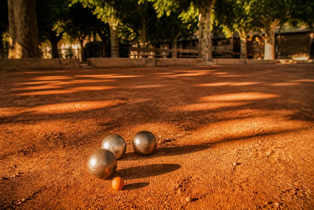 Boules de pétanque en acier et cochonnet sur un terrain de terre battue ocre