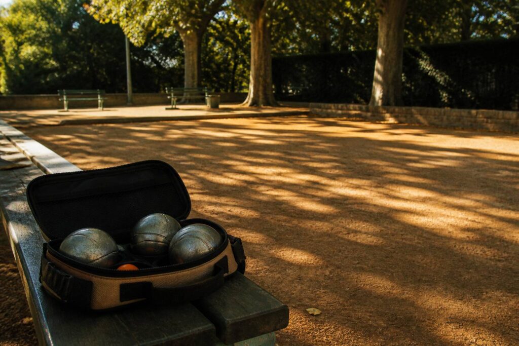 Sac à boules de pétanque ouvert avec trois boules en acier sur un banc de boulodrome