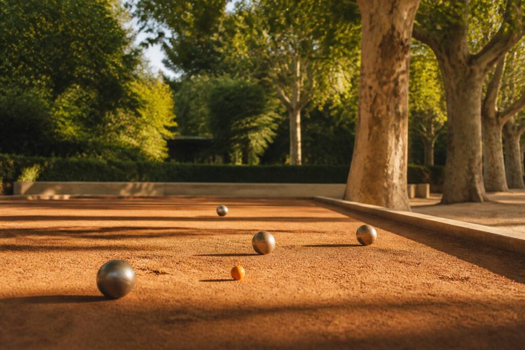 Terrain de pétanque en terre battue avec boules et platanes