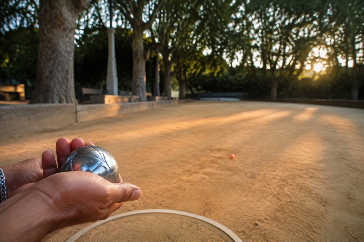 Main d'un joueur tenant une boule de pétanque au-dessus du cercle de lancer