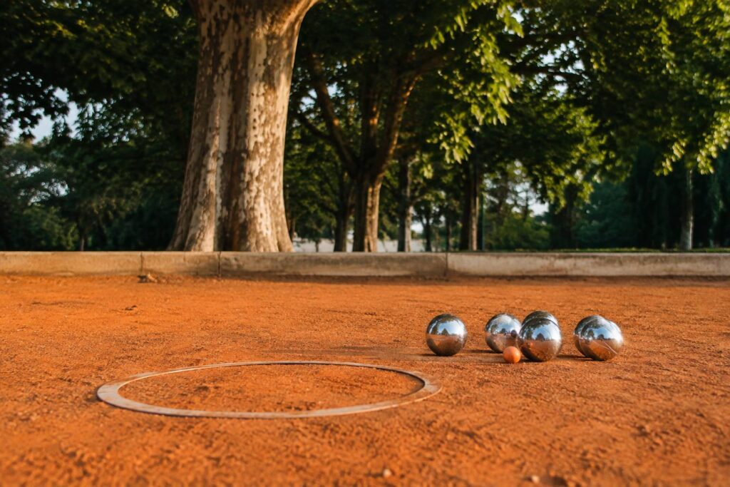 Boules de pétanque et cochonnet sur un terrain en terre battue au soleil couchant