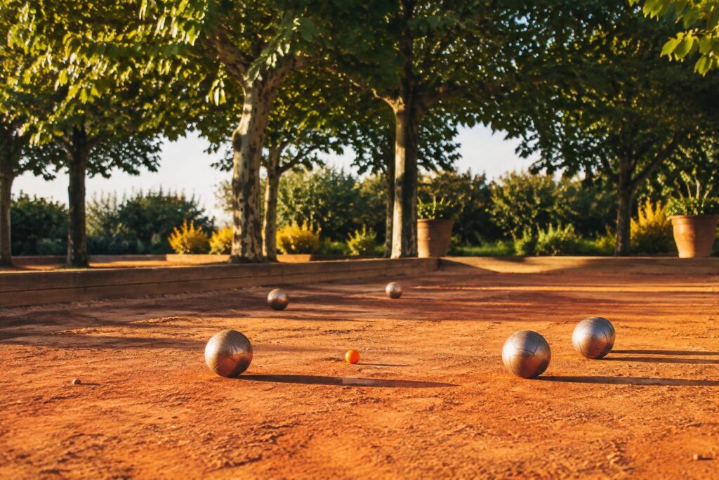 Boules de pétanque autour du cochonnet sur un terrain en terre battue ocre
